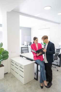 Meslektaşlar belgeli bir klasöre bakar ve iş konularını tartışırlar