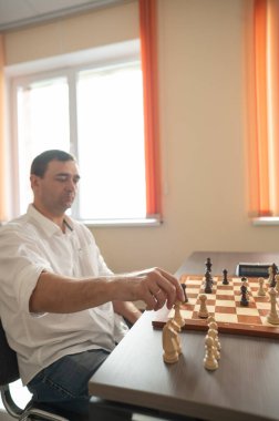 Orta yaşlı beyaz adam satranç oynuyor.