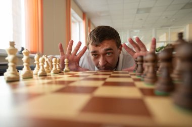 Orta yaşlı beyaz adam satranç oynuyor.