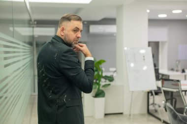 Ofiste kirli ceketli beyaz adam var.