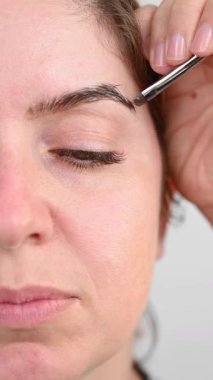 Beyaz kadın kaş boyama prosedürü uyguluyor.