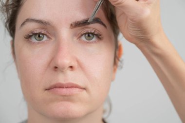 Beyaz kadın kaş boyama prosedürü uyguluyor.