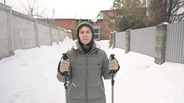 Kafkasyalı yaşlı kadın kışın İskandinav bastonlarıyla yürüyor
