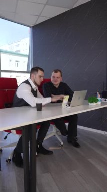 İki beyaz adam bir masada oturup iş tartışıyorlar.