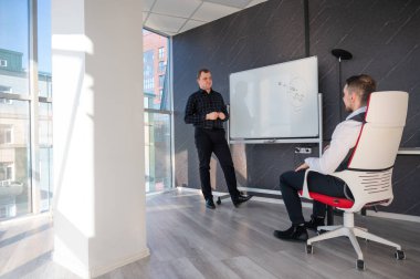 Beyaz bir kurulda iş tartışan iki beyaz adam.