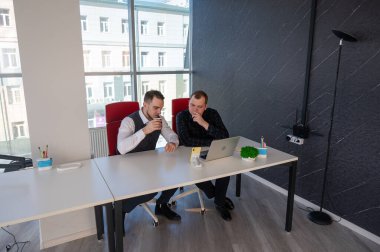 İki beyaz adam bir masada oturup iş tartışıyorlar.