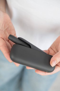 Bir kadın, tütün ısıtma sistemini şarj aletinden çıkarır. Elektronik sigara.