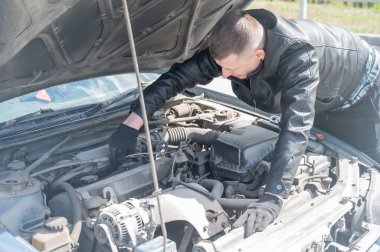 Bir adam arabasındaki bujileri değiştirir.
