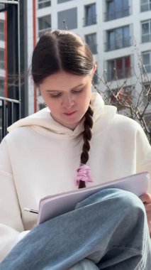 Açık havada kalemle çizim yapan beyaz bir kadın.