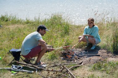 Kafkasyalı çift ateşte sosis kızartıyor.