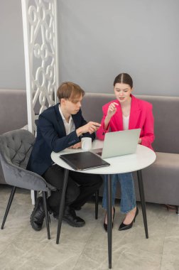 Meslektaşlar dizüstü bilgisayarda oturup iş konuşuyorlar.