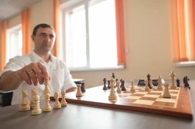 Orta yaşlı beyaz adam satranç oynuyor.