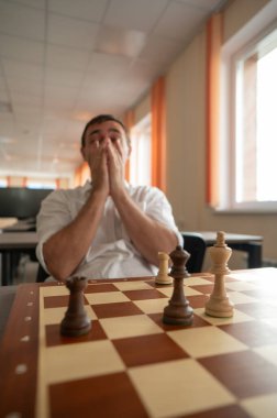 Orta yaşlı beyaz adam satranç oynuyor.