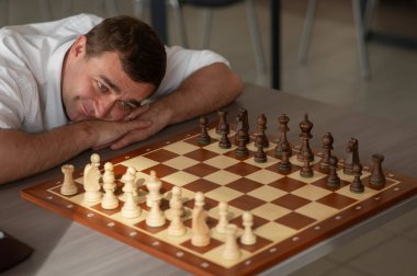 Orta yaşlı beyaz adam satranç oynuyor.