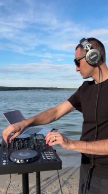 Beyaz adam plajda DJ olarak çalışıyor.