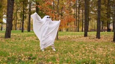 Hayalet kostümlü bir kadın sonbahar ormanında yürüyor. Cadılar Bayramı kostümü