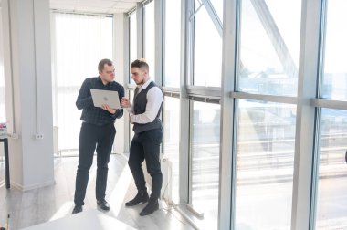 İki beyaz adam dizüstü bilgisayara bakıyor ve iş tartışıyorlar.