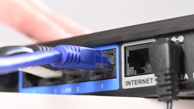 Bir kadın yönlendiricinin internet portuna kablo yerleştiriyor.