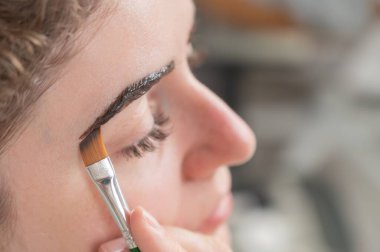 Beyaz kadın kaş boyama prosedürü uyguluyor.