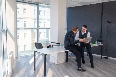 Ofiste iş tartışan iki beyaz adam. İşitme cihazı olan bir iş adamı.