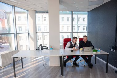 İki beyaz adam bir masada oturup iş tartışıyorlar.