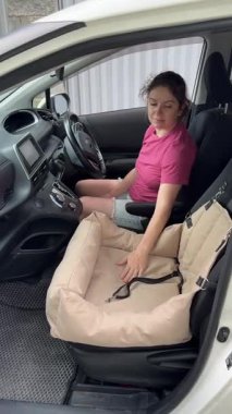 Beyaz kadın, Jack Russell Terrier köpeğini emniyet kemeriyle bağlıyor.