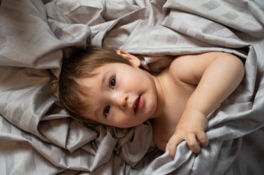 Beyaz tenli şirin bir çocuğun yatakta yatışının üst görüntüsü.