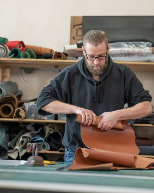 Beyaz sakallı adam bir atölyede bronzlaştırıcı olarak çalışıyor.