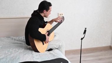 Genç adam kendini akıllı telefondan çekerken akustik gitar çalıyor. Parmak Biçimi