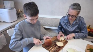 Kafkasyalı çocuk annesiyle evde hamburger pişiriyor.