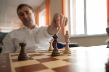 Orta yaşlı beyaz adam satranç oynuyor.