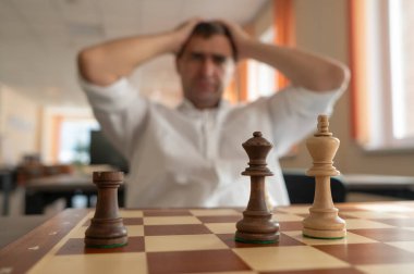 Orta yaşlı beyaz adam satranç oynuyor.