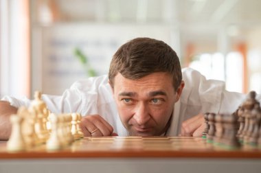 Orta yaşlı beyaz adam satranç oynuyor.