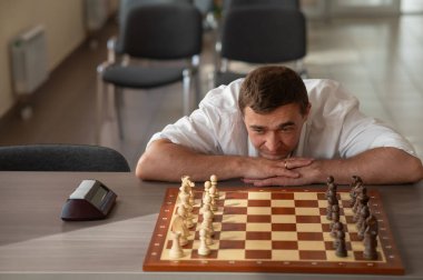 Orta yaşlı beyaz adam satranç oynuyor.