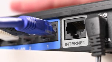 Bir kadın yönlendiricinin internet portuna kablo yerleştiriyor.