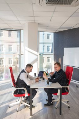 Masada otururken akıllı telefon kullanan iki beyaz adam.