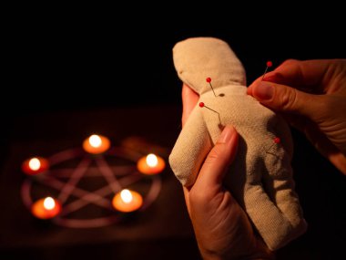 Kadın vudu bebeğine iğne batırıyor.