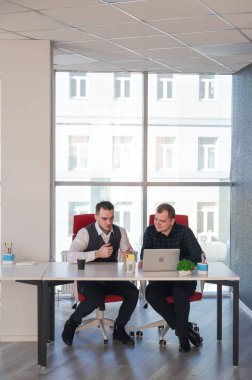 İki beyaz adam bir masada oturup iş tartışıyorlar.