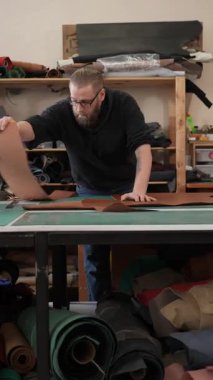 Beyaz sakallı adam bir atölyede bronzlaştırıcı olarak çalışıyor.