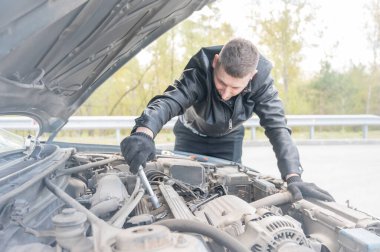 Bir adam arabasındaki bujileri değiştirir.