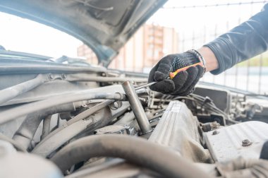 Bir adam arabasındaki bujileri değiştirir.