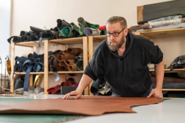 Beyaz sakallı adam bir atölyede bronzlaştırıcı olarak çalışıyor.