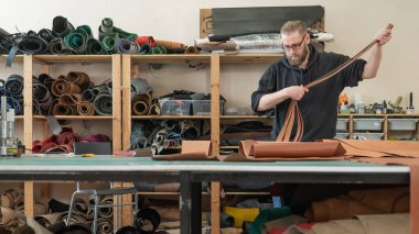 Beyaz sakallı adam bir atölyede bronzlaştırıcı olarak çalışıyor.