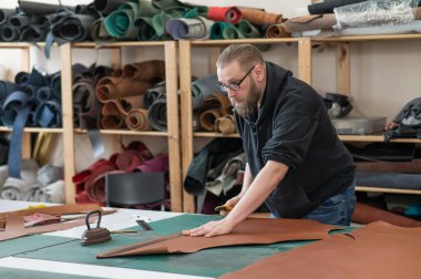 Beyaz sakallı adam bir atölyede bronzlaştırıcı olarak çalışıyor.