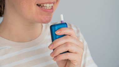 Elektronik sigara içen beyaz bir kadın. Tütün ısıtma sistemi