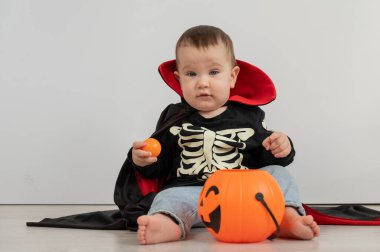 Beyaz arka planda şeker sepeti tutan Dracula Cadılar Bayramı kostümlü beyaz tatlı çocuk.