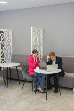 Meslektaşlar dizüstü bilgisayarda oturup iş konuşuyorlar.