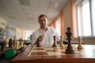 Orta yaşlı beyaz adam satranç oynuyor.