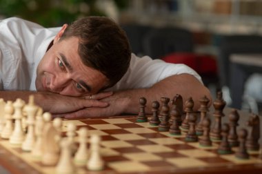 Orta yaşlı beyaz adam satranç oynuyor.