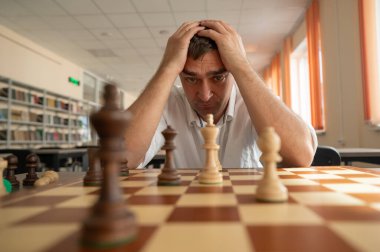 Orta yaşlı beyaz adam satranç oynuyor.